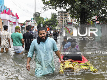 A family uses a raft on a flooded street to take shelter in the shelter house in the Mohipal area of Feni district in Chittagong division, B...