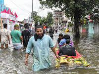 A family uses a raft on a flooded street to take shelter in the shelter house in the Mohipal area of Feni district in Chittagong division, B...