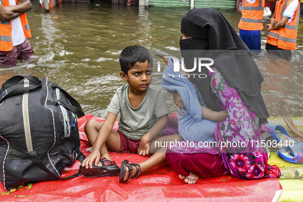 A family uses a raft on a flooded street to take shelter in the shelter house in the Mohipal area of Feni district in Chittagong division, B...