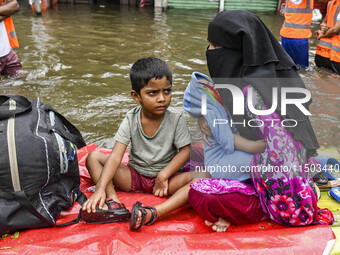 A family uses a raft on a flooded street to take shelter in the shelter house in the Mohipal area of Feni district in Chittagong division, B...