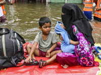 A family uses a raft on a flooded street to take shelter in the shelter house in the Mohipal area of Feni district in Chittagong division, B...