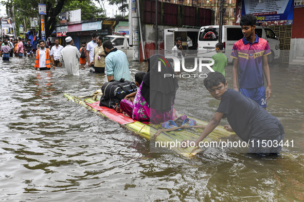 A family uses a raft on a flooded street to take shelter in the shelter house in the Mohipal area of Feni district in Chittagong division, B...