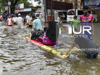 A family uses a raft on a flooded street to take shelter in the shelter house in the Mohipal area of Feni district in Chittagong division, B...