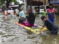 A family uses a raft on a flooded street to take shelter in the shelter house in the Mohipal area of Feni district in Chittagong division, B...