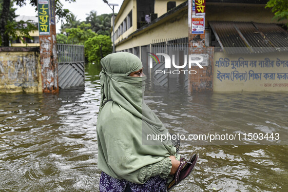 A woman wades through floodwaters in the Mohipal area of Feni district in Chittagong division, Bangladesh, on August 23, 2024. At least 13 p...