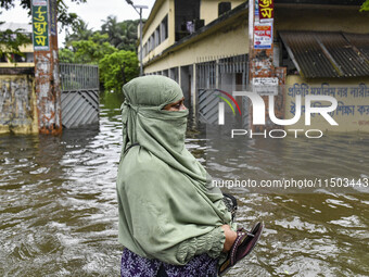 A woman wades through floodwaters in the Mohipal area of Feni district in Chittagong division, Bangladesh, on August 23, 2024. At least 13 p...