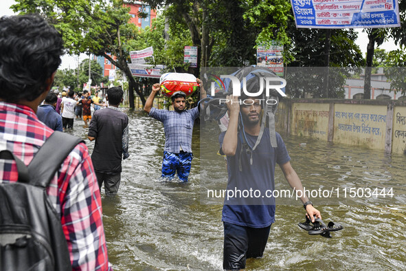 People wade through floodwaters in the Mohipal area of Feni district in Chittagong division, Bangladesh, on August 23, 2024. At least 13 peo...