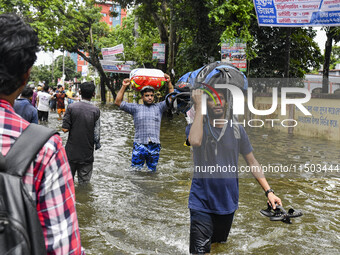 People wade through floodwaters in the Mohipal area of Feni district in Chittagong division, Bangladesh, on August 23, 2024. At least 13 peo...