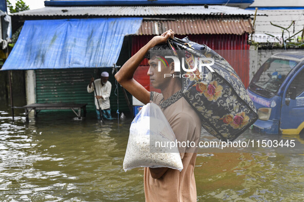 People wade through floodwaters in the Mohipal area of Feni district in Chittagong division, Bangladesh, on August 23, 2024. At least 13 peo...