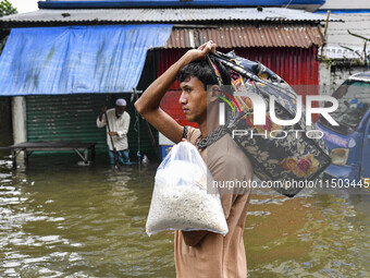 People wade through floodwaters in the Mohipal area of Feni district in Chittagong division, Bangladesh, on August 23, 2024. At least 13 peo...