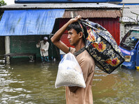 People wade through floodwaters in the Mohipal area of Feni district in Chittagong division, Bangladesh, on August 23, 2024. At least 13 peo...