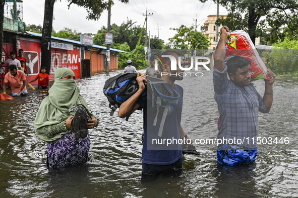 People wade through floodwaters in the Mohipal area of Feni district in Chittagong division, Bangladesh, on August 23, 2024. At least 13 peo...