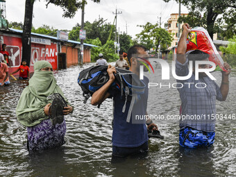 People wade through floodwaters in the Mohipal area of Feni district in Chittagong division, Bangladesh, on August 23, 2024. At least 13 peo...