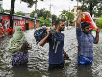 People wade through floodwaters in the Mohipal area of Feni district in Chittagong division, Bangladesh, on August 23, 2024. At least 13 peo...