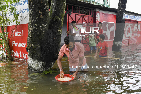 A man washes rice in a flooded street in the Mohipal area of Feni district in Chittagong division, Bangladesh, on August 23, 2024. At least...