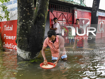 A man washes rice in a flooded street in the Mohipal area of Feni district in Chittagong division, Bangladesh, on August 23, 2024. At least...