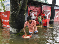 A man washes rice in a flooded street in the Mohipal area of Feni district in Chittagong division, Bangladesh, on August 23, 2024. At least...