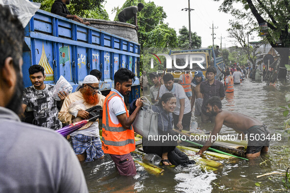 Volunteers rescue a flood-affected woman in the Mohipal area of Feni district in Chittagong division, Bangladesh, on August 23, 2024. At lea...