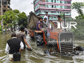 Volunteers carry a boat on a tractor to help flood-affected people in the Mohipal area of Feni district in Chittagong division, Bangladesh,...