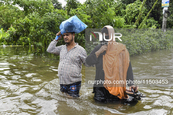 People wade through floodwaters in the Mohipal area of Feni district in Chittagong division, Bangladesh, on August 23, 2024. At least 13 peo...