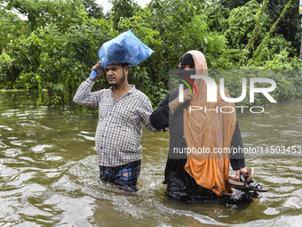 People wade through floodwaters in the Mohipal area of Feni district in Chittagong division, Bangladesh, on August 23, 2024. At least 13 peo...