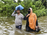 People wade through floodwaters in the Mohipal area of Feni district in Chittagong division, Bangladesh, on August 23, 2024. At least 13 peo...