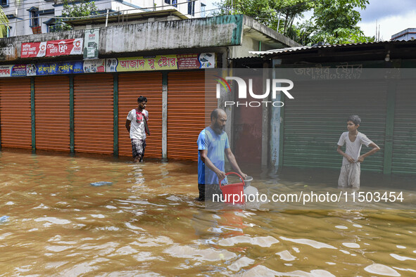 People wade through floodwaters in the Mohipal area of Feni district in Chittagong division, Bangladesh, on August 23, 2024. At least 13 peo...