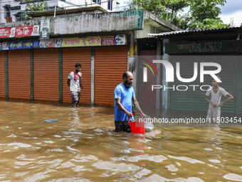 People wade through floodwaters in the Mohipal area of Feni district in Chittagong division, Bangladesh, on August 23, 2024. At least 13 peo...