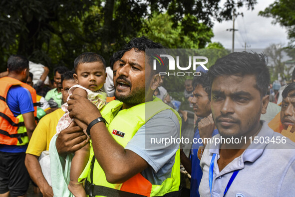 Volunteers rescue a flood-affected child in the Mohipal area of Feni district in Chittagong division, Bangladesh, on August 23, 2024. At lea...