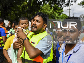 Volunteers rescue a flood-affected child in the Mohipal area of Feni district in Chittagong division, Bangladesh, on August 23, 2024. At lea...