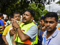 Volunteers rescue a flood-affected child in the Mohipal area of Feni district in Chittagong division, Bangladesh, on August 23, 2024. At lea...