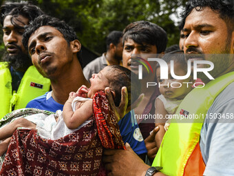 Volunteers rescue a flood-affected 10-day-old child in the Mohipal area of Feni district in Chittagong division, Bangladesh, on August 23, 2...