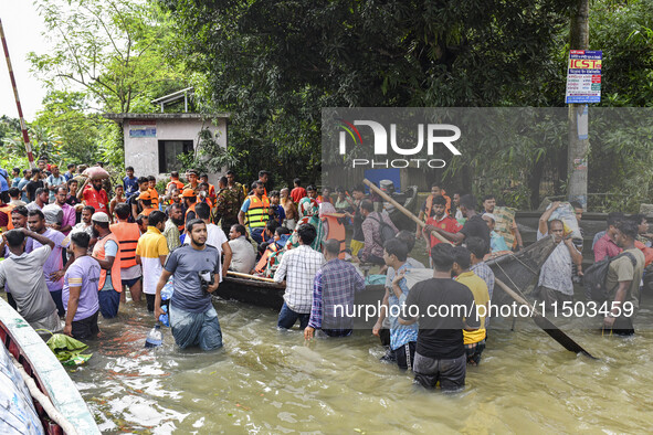 People wade through floodwaters in the Mohipal area of Feni district in Chittagong division, Bangladesh, on August 23, 2024. At least 13 peo...