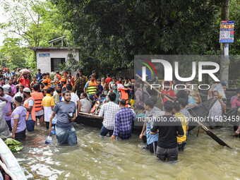 People wade through floodwaters in the Mohipal area of Feni district in Chittagong division, Bangladesh, on August 23, 2024. At least 13 peo...