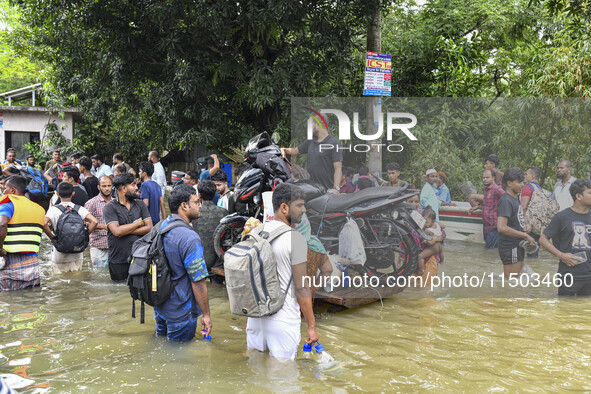 People wade through floodwaters in the Mohipal area of Feni district in Chittagong division, Bangladesh, on August 23, 2024. At least 13 peo...