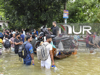 People wade through floodwaters in the Mohipal area of Feni district in Chittagong division, Bangladesh, on August 23, 2024. At least 13 peo...