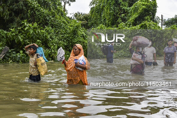 People wade through floodwaters in the Mohipal area of Feni district in Chittagong division, Bangladesh, on August 23, 2024. At least 13 peo...