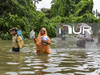 People wade through floodwaters in the Mohipal area of Feni district in Chittagong division, Bangladesh, on August 23, 2024. At least 13 peo...