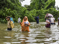 People wade through floodwaters in the Mohipal area of Feni district in Chittagong division, Bangladesh, on August 23, 2024. At least 13 peo...