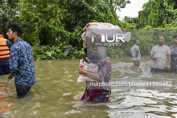 People wade through floodwaters in the Mohipal area of Feni district in Chittagong division, Bangladesh, on August 23, 2024. At least 13 peo...