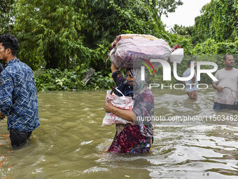 People wade through floodwaters in the Mohipal area of Feni district in Chittagong division, Bangladesh, on August 23, 2024. At least 13 peo...