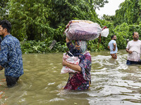 People wade through floodwaters in the Mohipal area of Feni district in Chittagong division, Bangladesh, on August 23, 2024. At least 13 peo...