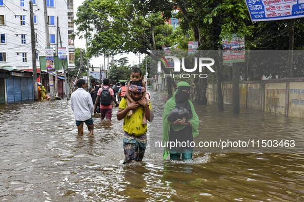 People wade through floodwaters in the Mohipal area of Feni district in Chittagong division, Bangladesh, on August 23, 2024. At least 13 peo...