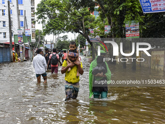 People wade through floodwaters in the Mohipal area of Feni district in Chittagong division, Bangladesh, on August 23, 2024. At least 13 peo...