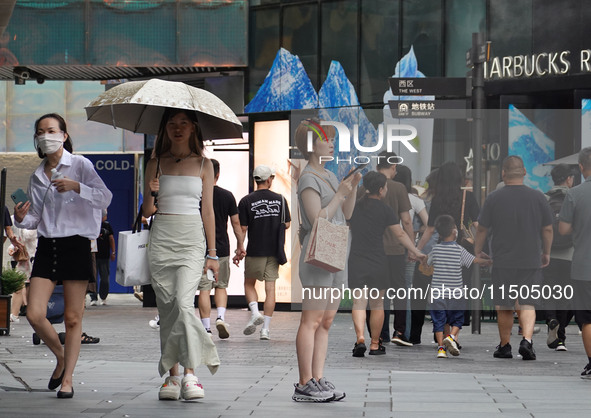 People visit Taikoo Li, a trendy fashion district in Sanlitun, in Beijing, China, on August 18, 2024. 