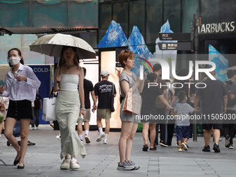 People visit Taikoo Li, a trendy fashion district in Sanlitun, in Beijing, China, on August 18, 2024. (