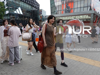 People visit Taikoo Li, a trendy fashion district in Sanlitun, in Beijing, China, on August 18, 2024. (