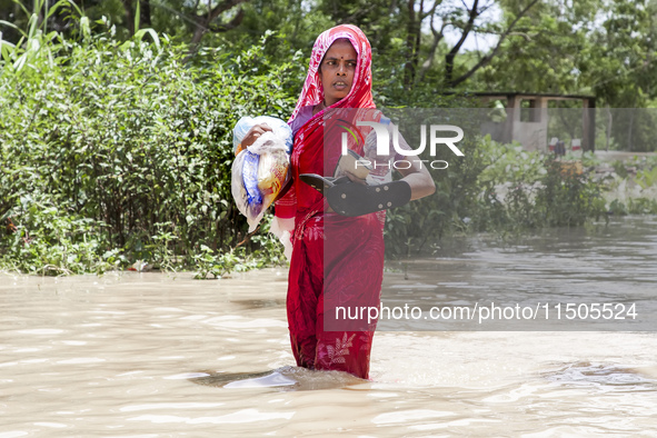 Pedestrians wade through flooded roads in floodwaters up to their waists and knees in Bishumia Hat, Mirsarai, southern Bangladesh. At least...