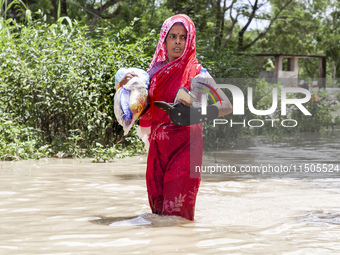 Pedestrians wade through flooded roads in floodwaters up to their waists and knees in Bishumia Hat, Mirsarai, southern Bangladesh. At least...