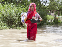 Pedestrians wade through flooded roads in floodwaters up to their waists and knees in Bishumia Hat, Mirsarai, southern Bangladesh. At least...